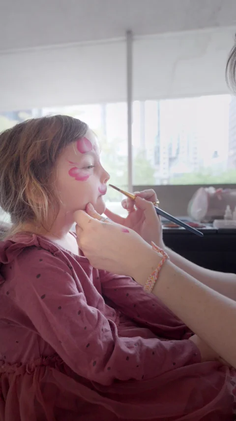 A young concertgoer having her face painted pink